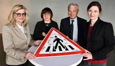 Von Botschaftsangehörigen signiert: Ein Fußgängerschild aus dem Kosovo für die „Internationale Sammlung originaler Verkehrszeichen für Fußgängerüberwege“ halten Kulturamtleiterin Carola Metz, Sammlerin Doris Gutermuth, Bundeswehr-Oberst a.D. Hans Werner Patzki und Kulturdezernentin Susanne Völker in den Händen 