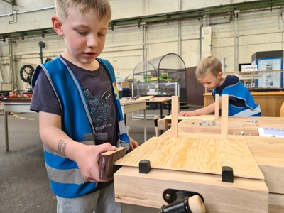 Finn und Leo schleifen ihr Spielbrett an der Kinderwerkbank.