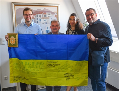 © Stadt Hanau / Moritz Göbel - Als äußeres Zeichen des Dankes überreichte Viktor Kosohlodiuk (2. v.l.) das Wappen der Stadt Mykolajiw und eine ukrainische Flagge an Hanaus Bürgermeister Dr. Maximilian Bieri (Foto links). Die Hilfskonvois und die Delegationsreise organisieren Nicole Alice Deeg und Niko Deeg von der Jüdisch-chassidische Kultusgemeinde Breslev Deutschland in Hanau.