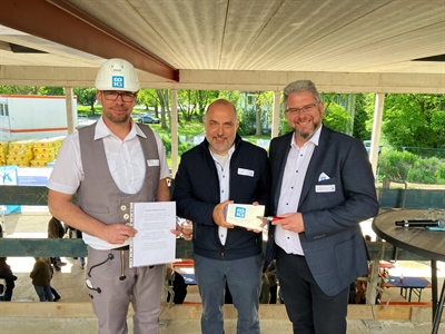 © Stadt Arnsberg - Zum Richtfest am Bürgerzentrum an der Ruhr nahm der Arnsberger Bürgermeister Ralf Paul Bittner eine eigens gravierte Maurerkelle vom Geschäftsführer der beauftragten Baufirma BIG Glowienka, Uwe Fey, entgegen und freute sich über den Richtspruch von Polier Tobias Heggen.